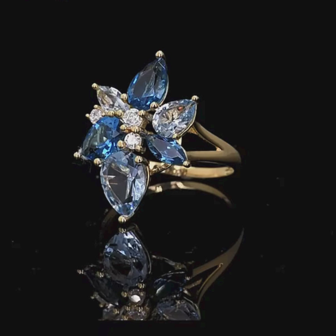 Gold-plated ring with a cluster of blue and clear gemstones in marquise and pear cuts arranged like flower petals

