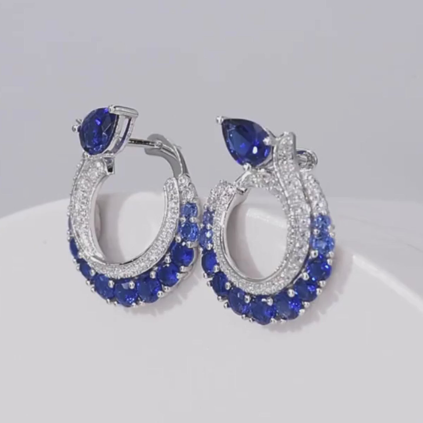 Sterling silver hoop earrings with pavé and deep blue pear-shaped sapphires.

