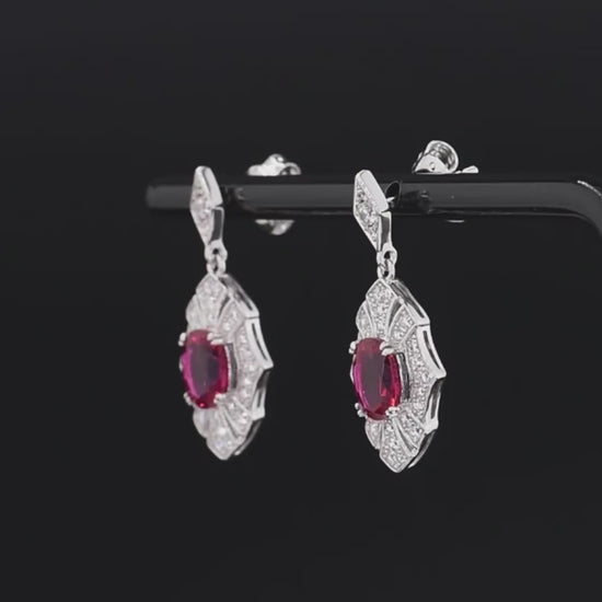 Rubino earrings with deep red oval stones framed in intricate silver settings accented by small white crystals.

