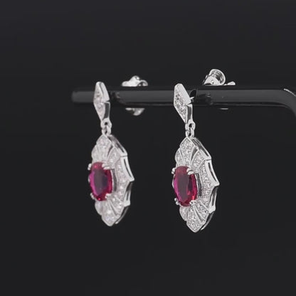 Rubino earrings with deep red oval stones framed in intricate silver settings accented by small white crystals.


