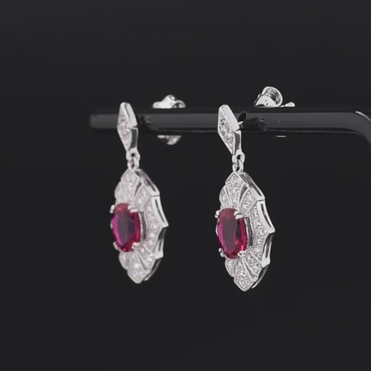 Rubino earrings with deep red oval stones framed in intricate silver settings accented by small white crystals.

