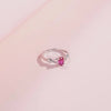 Gold-plated ring with an oval pink gemstone and twisted infinity-style band

