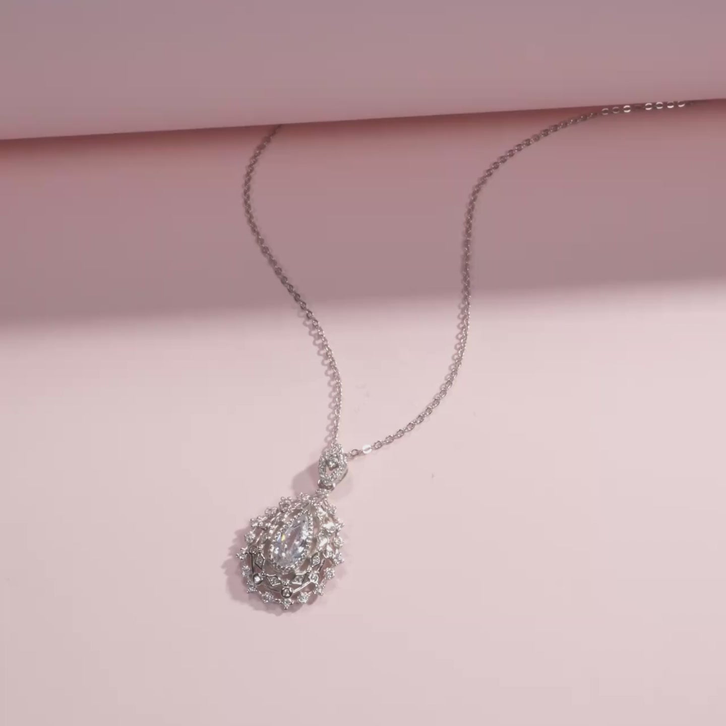 Ornate silver necklace with an intricate teardrop pendant, featuring a central pear-cut white gemstone, part of the Bianco Nero collection.

