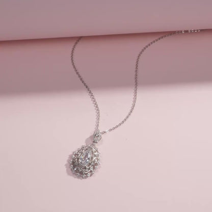 Ornate silver necklace with an intricate teardrop pendant, featuring a central pear-cut white gemstone, part of the Bianco Nero collection.

