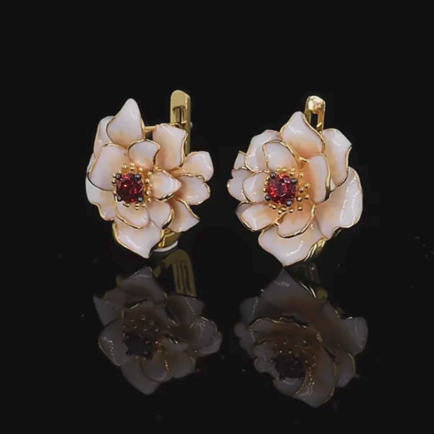Jewelry set with white enamel floral design and red gemstone center, including a ring, earrings, and pendant.

