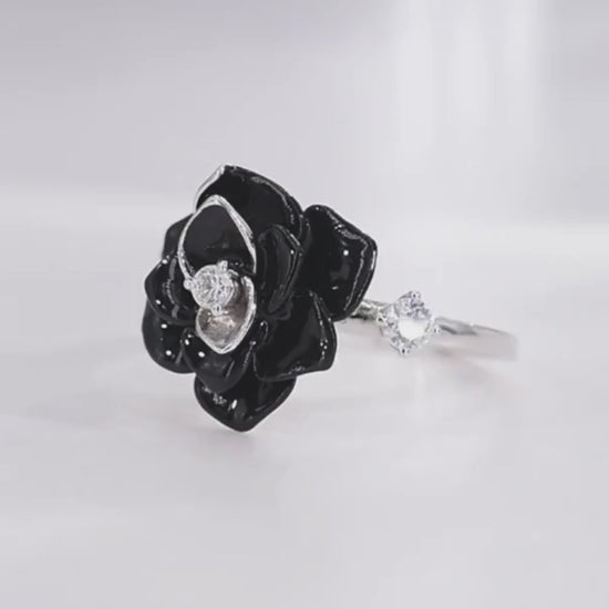 Silver ring with a black enamel rose centerpiece and two clear gemstones on the band.

