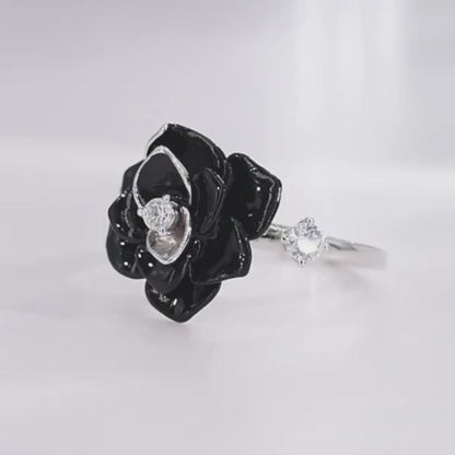 Silver ring with a black enamel rose centerpiece and two clear gemstones on the band.

