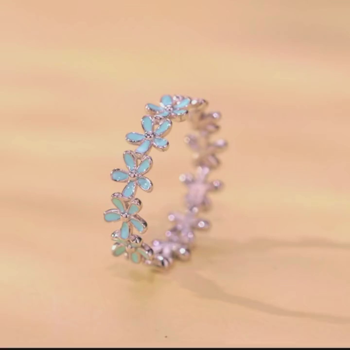 Silver floral band ring with alternating blue enamel and plain silver daisy motifs

