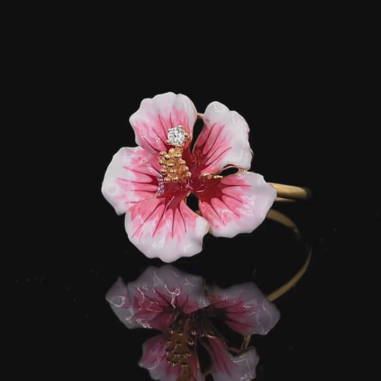 Prato ring shaped like a blooming hibiscus flower in pink enamel with golden stamen and a single sparkling white stone.

