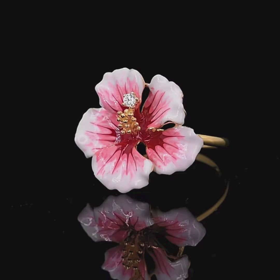 Prato ring shaped like a blooming hibiscus flower in pink enamel with golden stamen and a single sparkling white stone.

