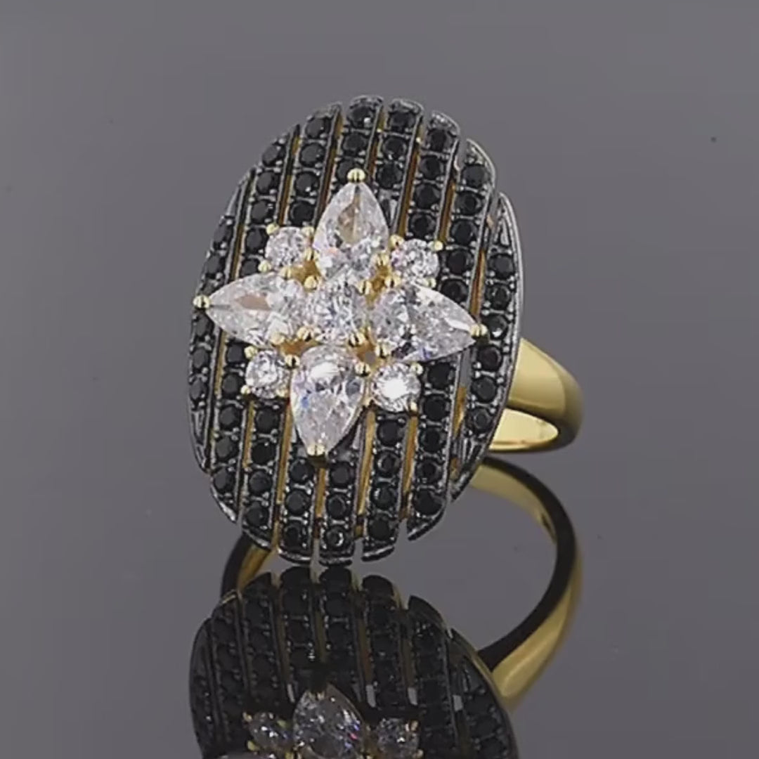 Gold ring with an oval black and white starburst design featuring clear marquise and round stones

