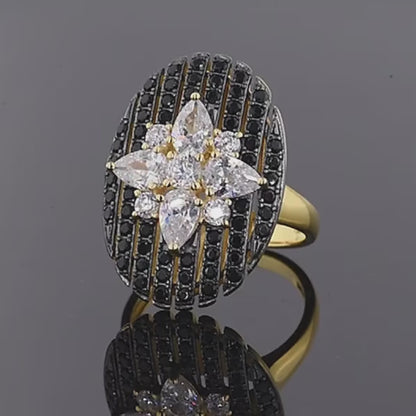 Gold ring with an oval black and white starburst design featuring clear marquise and round stones

