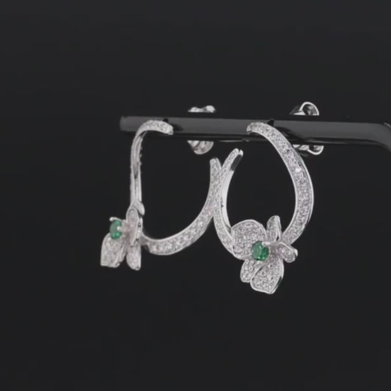 Silver stud earrings with open circle design, pavé stones, and green gemstone floral accents

