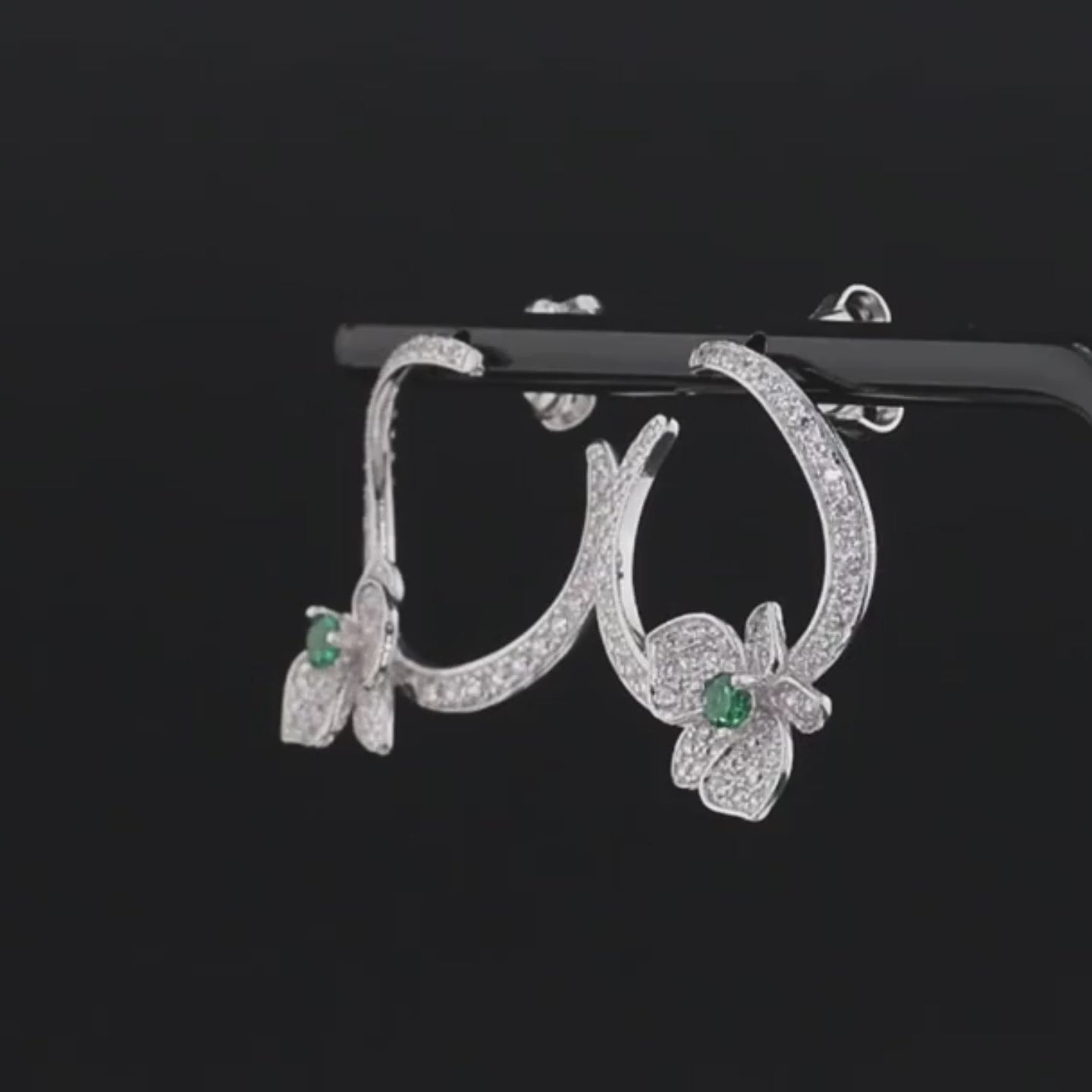 Silver stud earrings with open circle design, pavé stones, and green gemstone floral accents


