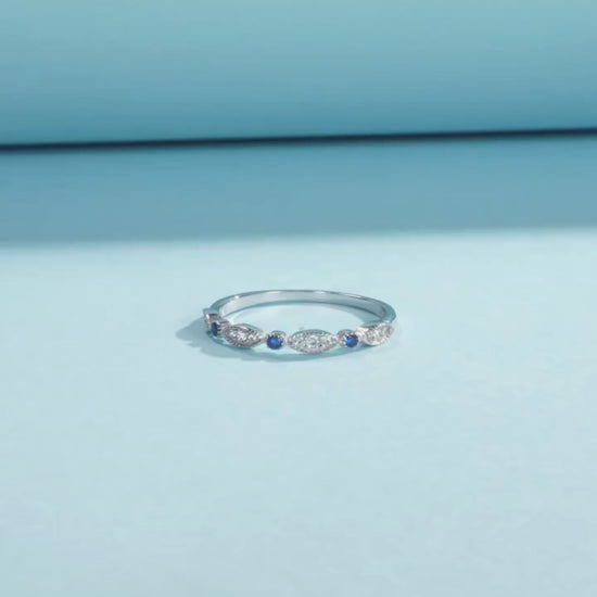 Sterling silver band with alternating marquise shapes and small round blue and clear stones


