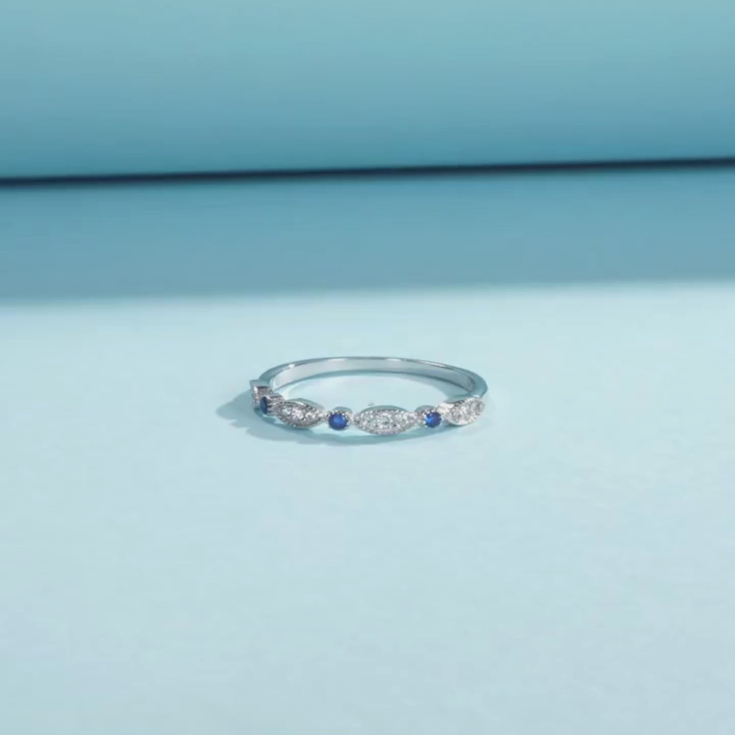 Sterling silver band with alternating marquise shapes and small round blue and clear stones

