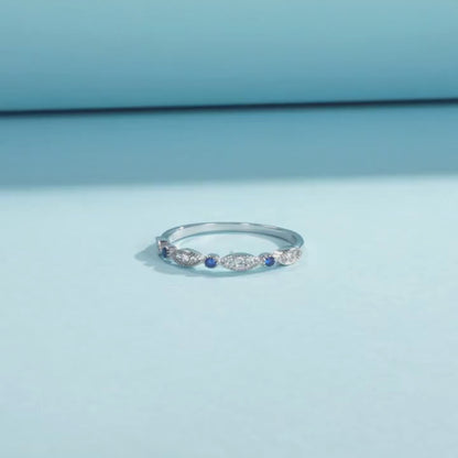 Sterling silver band with alternating marquise shapes and small round blue and clear stones

