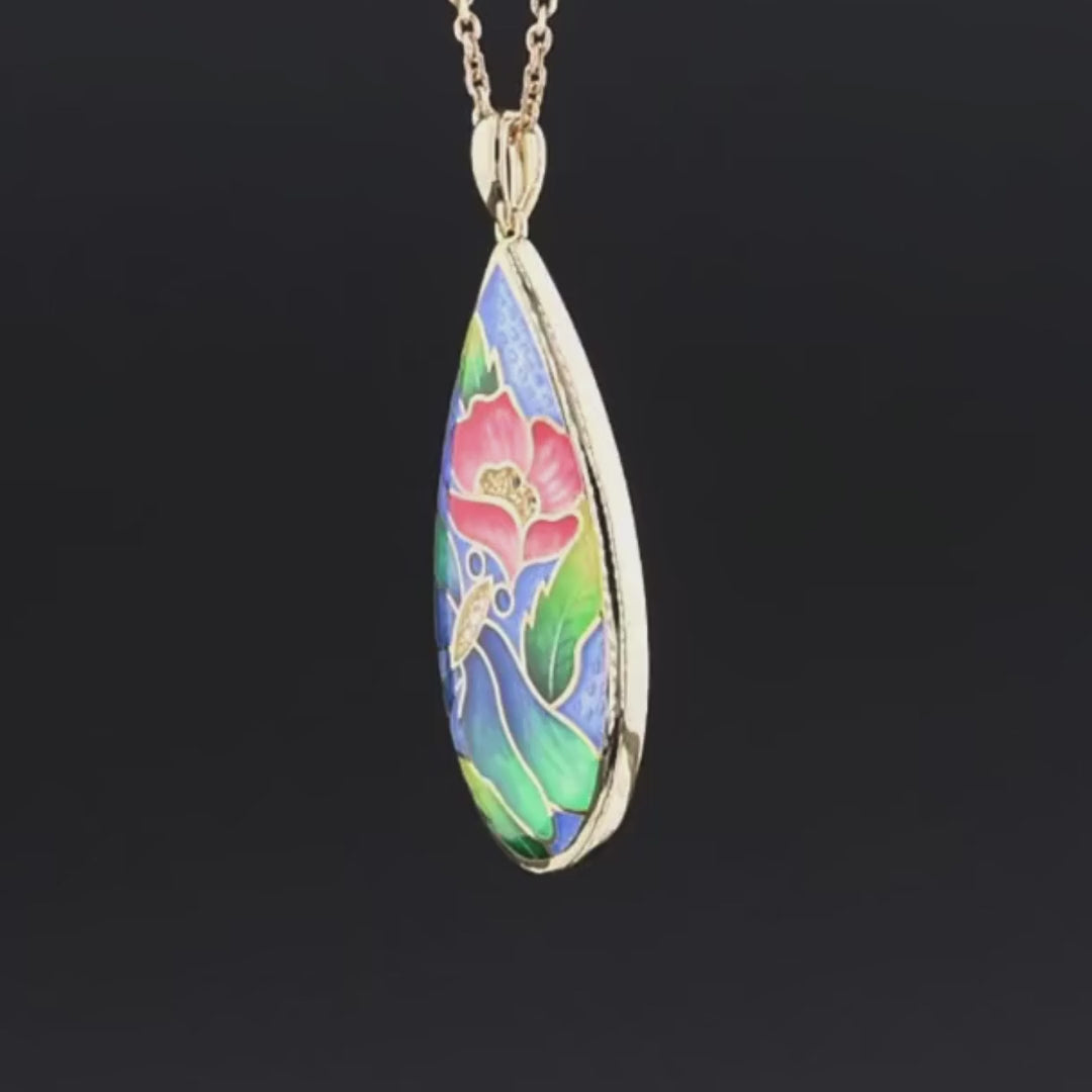 Teardrop-shaped gold pendant with a vivid enamel design featuring a red flower, blue butterfly, green leaves, and subtle gemstone accents