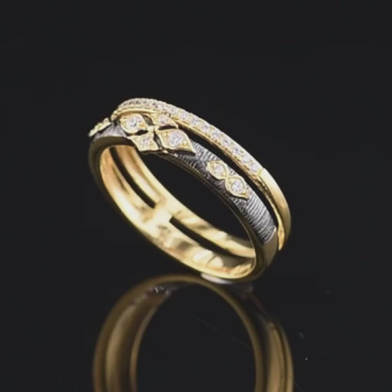 Gold ring with diamond accents and a contrasting textured black band featuring a geometric floral design.

