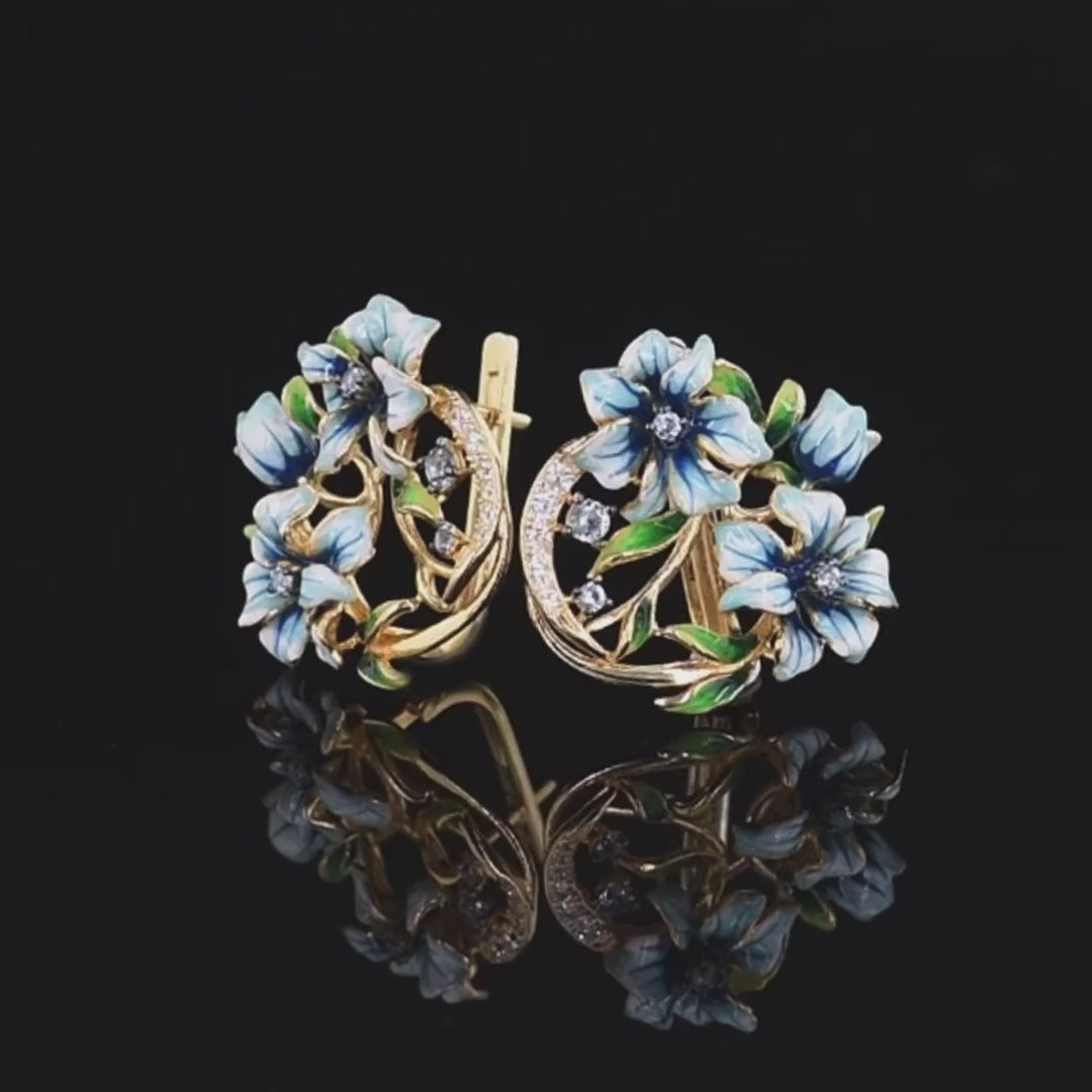 Gold-tone earrings with white and blue enamel flowers and crystal accents

