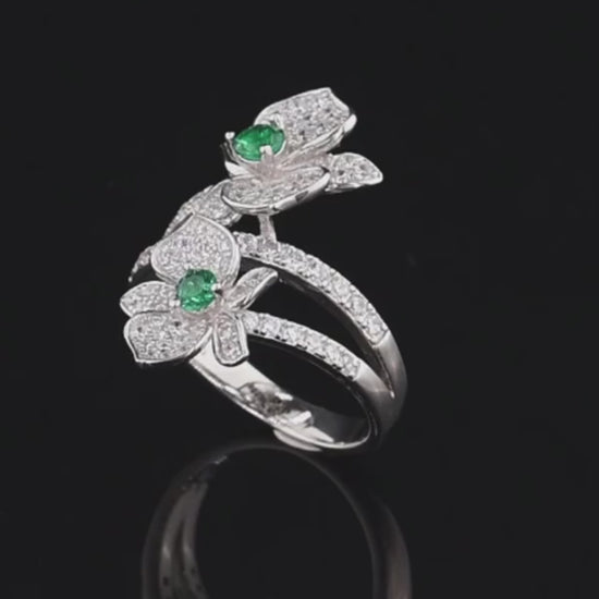 Sterling silver ring with twin pavé-set floral forms and vivid green center stones

