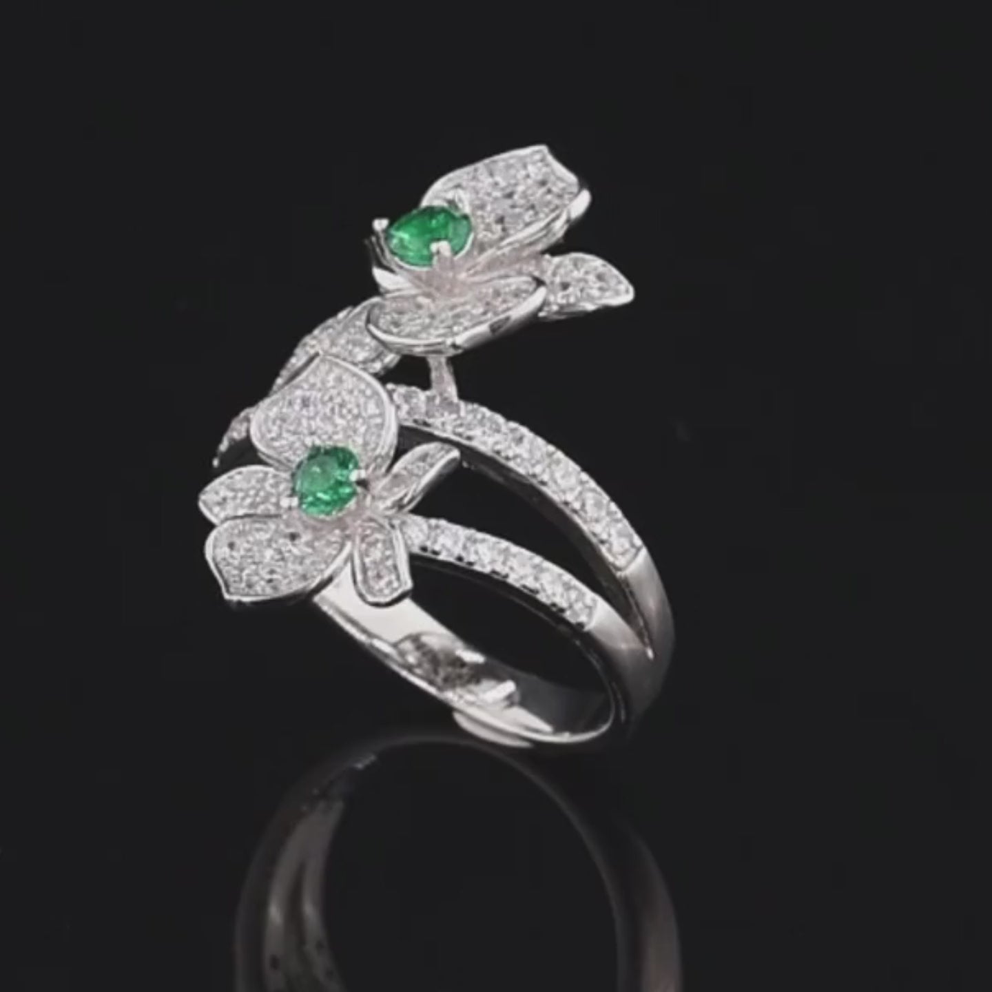 Sterling silver ring with twin pavé-set floral forms and vivid green center stones

