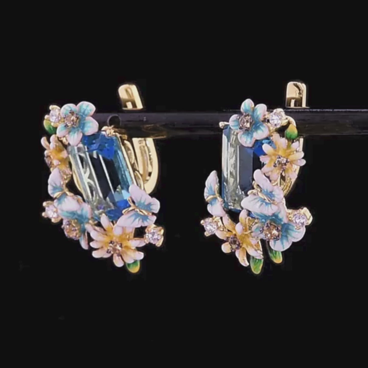 Gold floral earrings with large blue emerald-cut stones and pastel enamel blossoms

