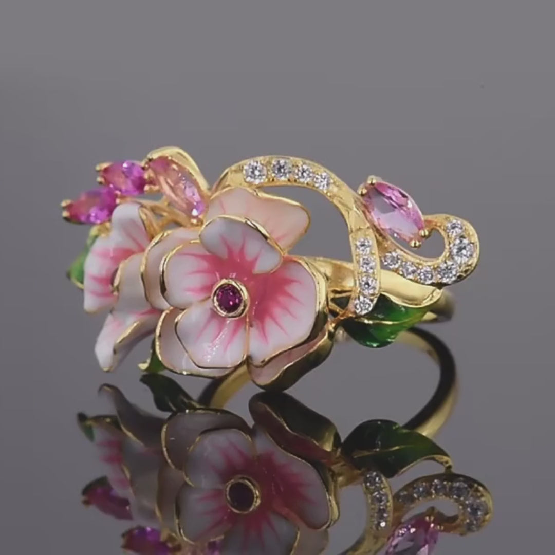 Prato ring with hand-painted pink flowers, green enamel leaves, and pink marquise-cut stones on a gold band.


