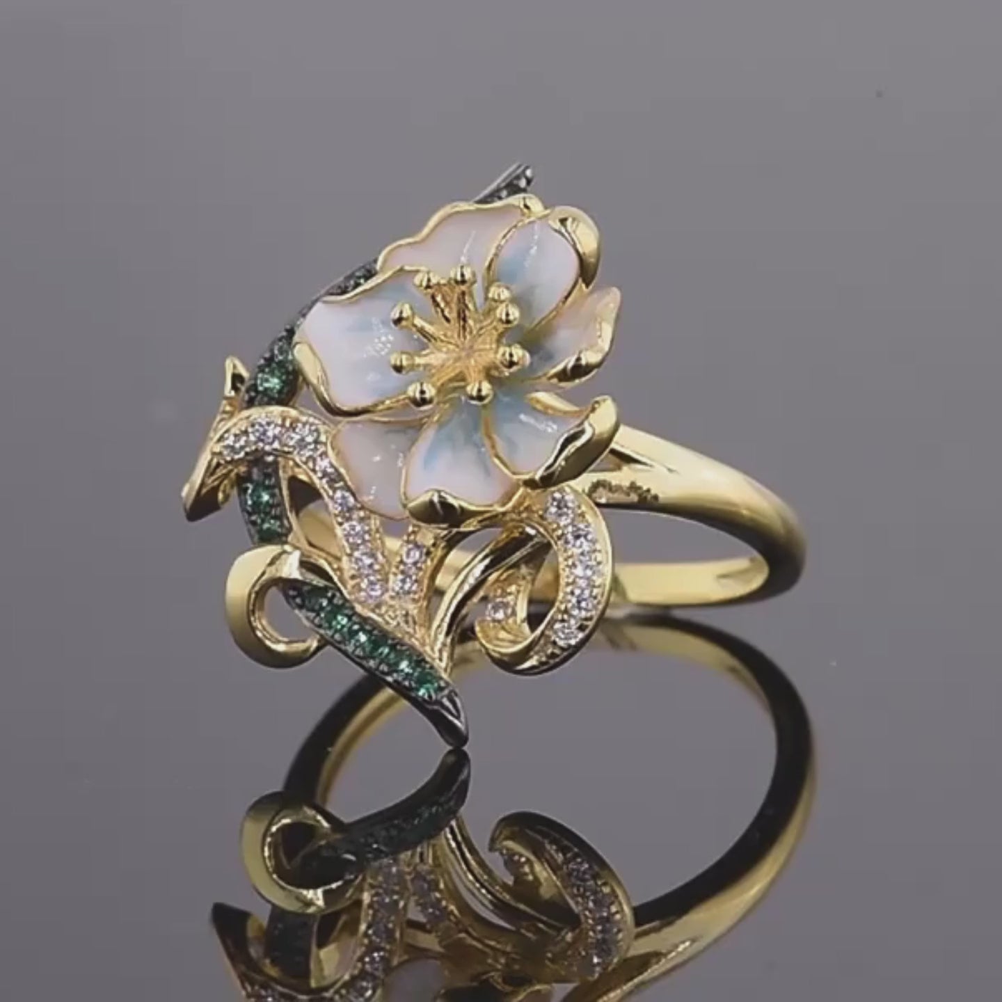 Gold ring with pastel enamel flower, green and clear stones on entwined vine-like details, from the Nastro Verde line.

