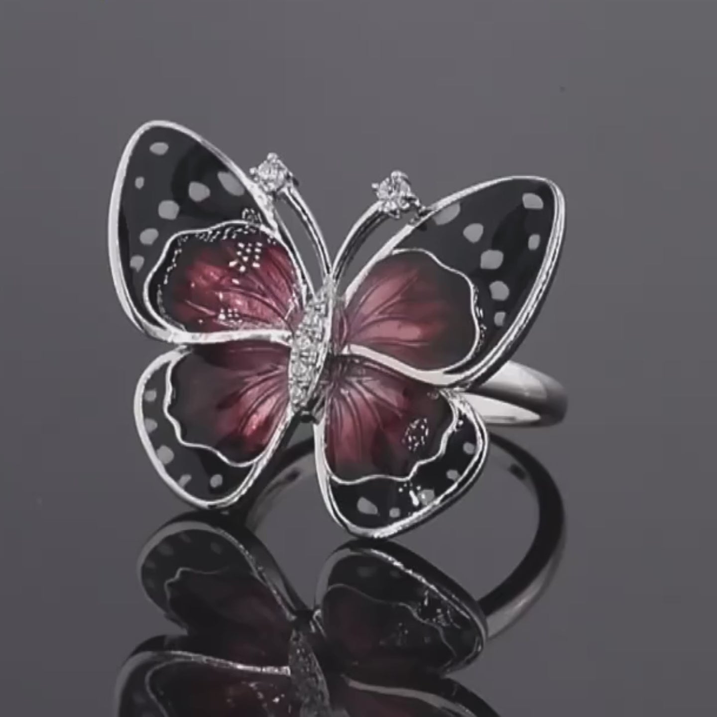 Butterfly-inspired ring with red enamel wings, black accents, and white dot details.

